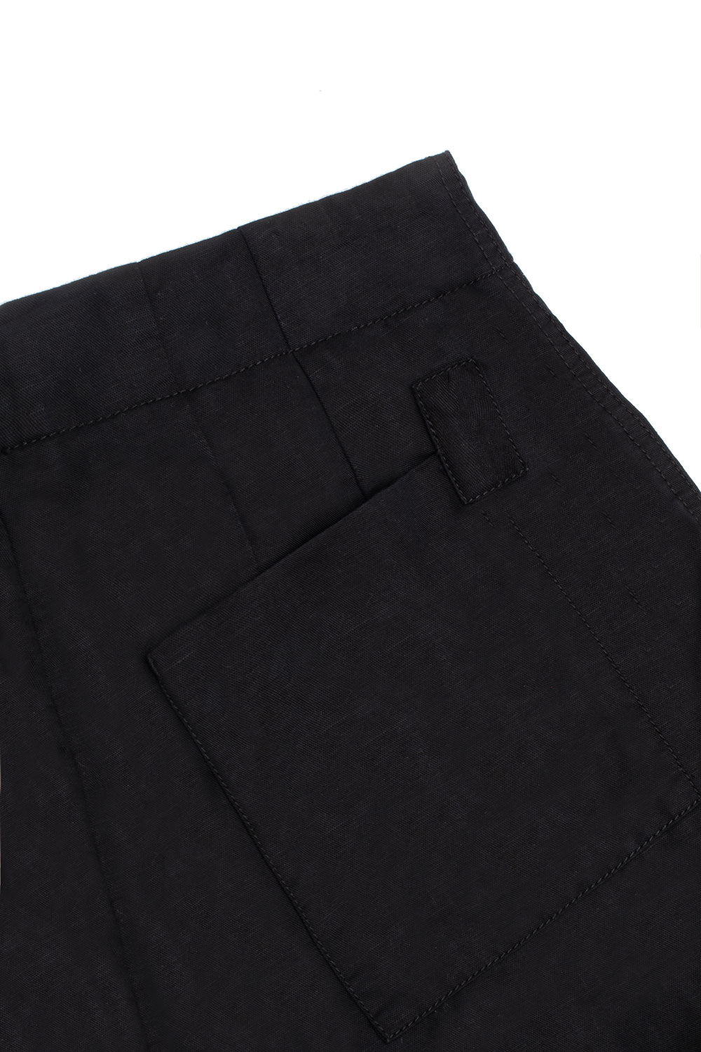 Close up of the back patch pockets of the Amelia Wide Leg Culotte Trousers in black organic cotton and linen. The black cotton herringbone tape on the corner of the patch pocket can be seen in the image as a detail.